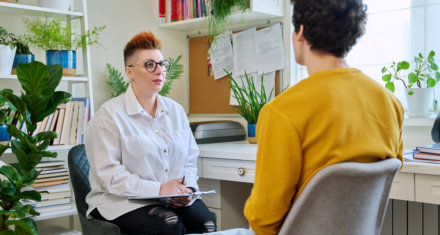 Female psychologist mental therapist working with young guy in office