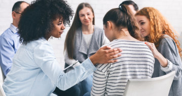 group of people consoling the depress woman