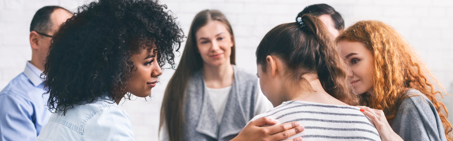 group of people consoling the depress woman